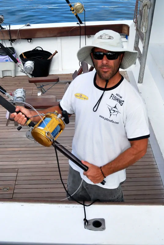 fisherman with deep sea fishing rod fisherman holds a deep sea fishing rod inside the boat in Puerto de los Cristianos